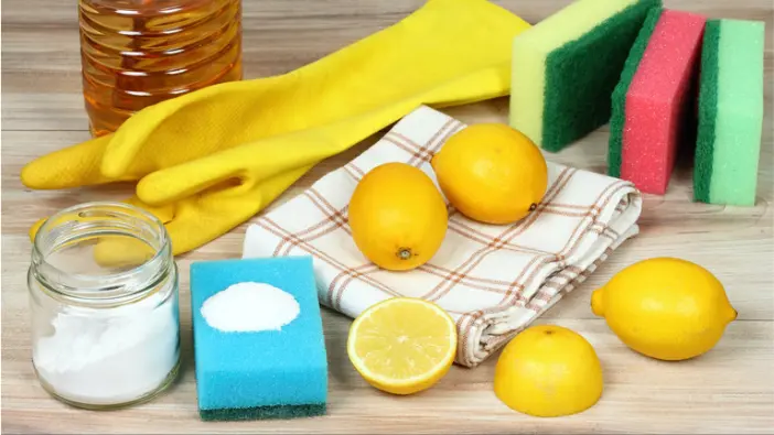 Various cleaning supplies, including a vibrant lemon and an abundance of sponges, ready for household cleaning activities.