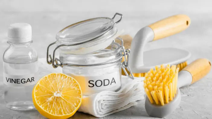 A collection of cleaning products featuring lemon, vinegar, and soap arranged on a countertop.